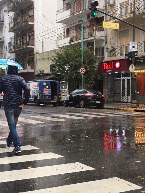 Few passers-by with umbrellas and masks